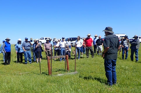 Symposium of people gathered together in front of a new marker on the trail.